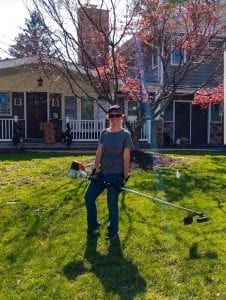 Lawn care provider holding weed whip on Philadelphia front lanw