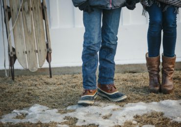 Two young people, a boy and girl standing in a yard in winter.