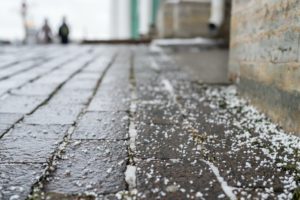 Closeup of technical salt grains on icy sidewalk surface in winter, used for melting ice and snow.