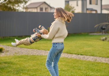 Joyful woman whirls child on lawn in Detroit Michigan