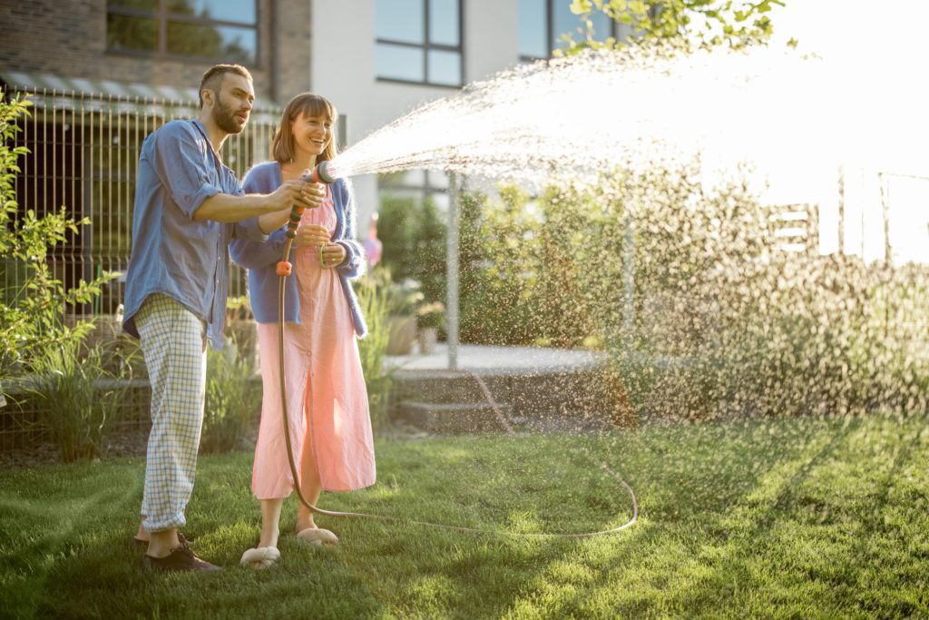 Lovely couple watering lawn at backyard