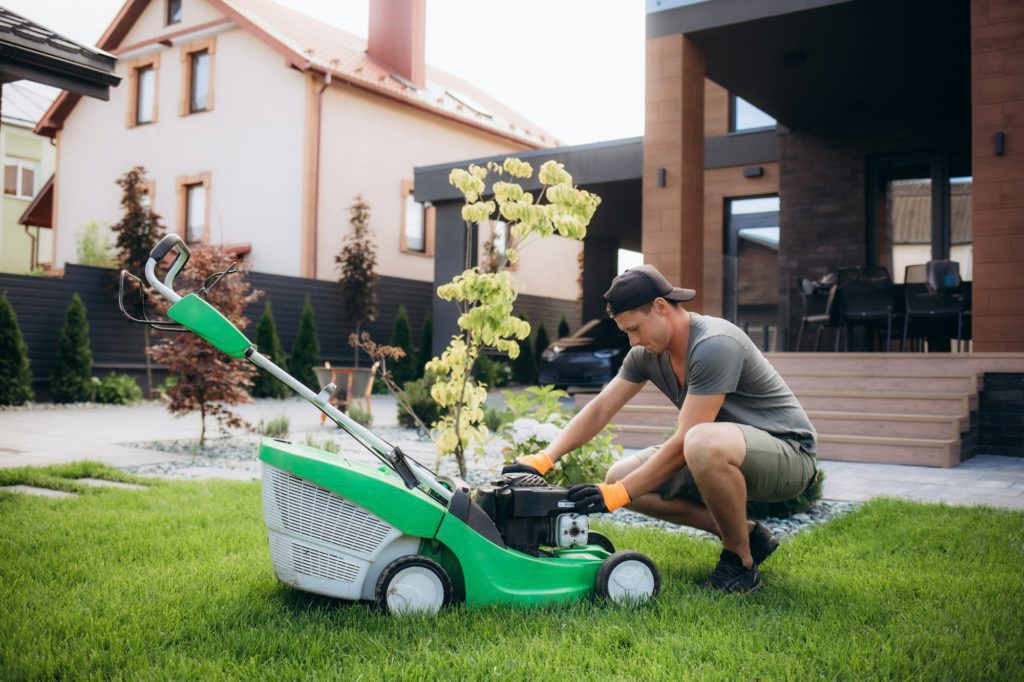 The gardener repairs the lawnmower. Garden maintenance.