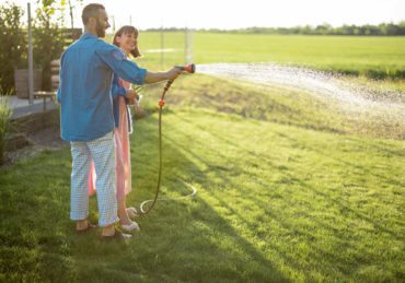 Lovely couple watering lawn at backyard
