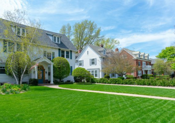 Row of traditional suburban homes with lush green front lawns in nice residential neighborhood