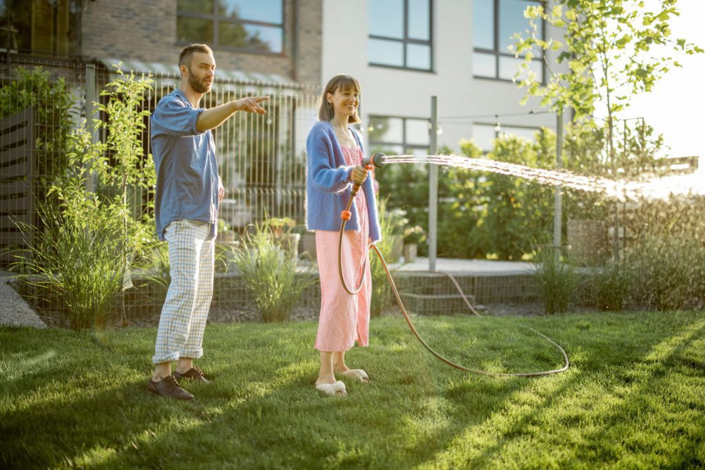 Lovely couple watering lawn at backyard