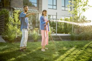 Lovely couple watering lawn at backyard