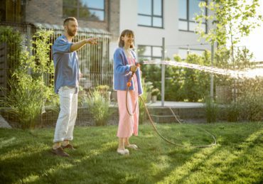 Lovely couple watering lawn at backyard