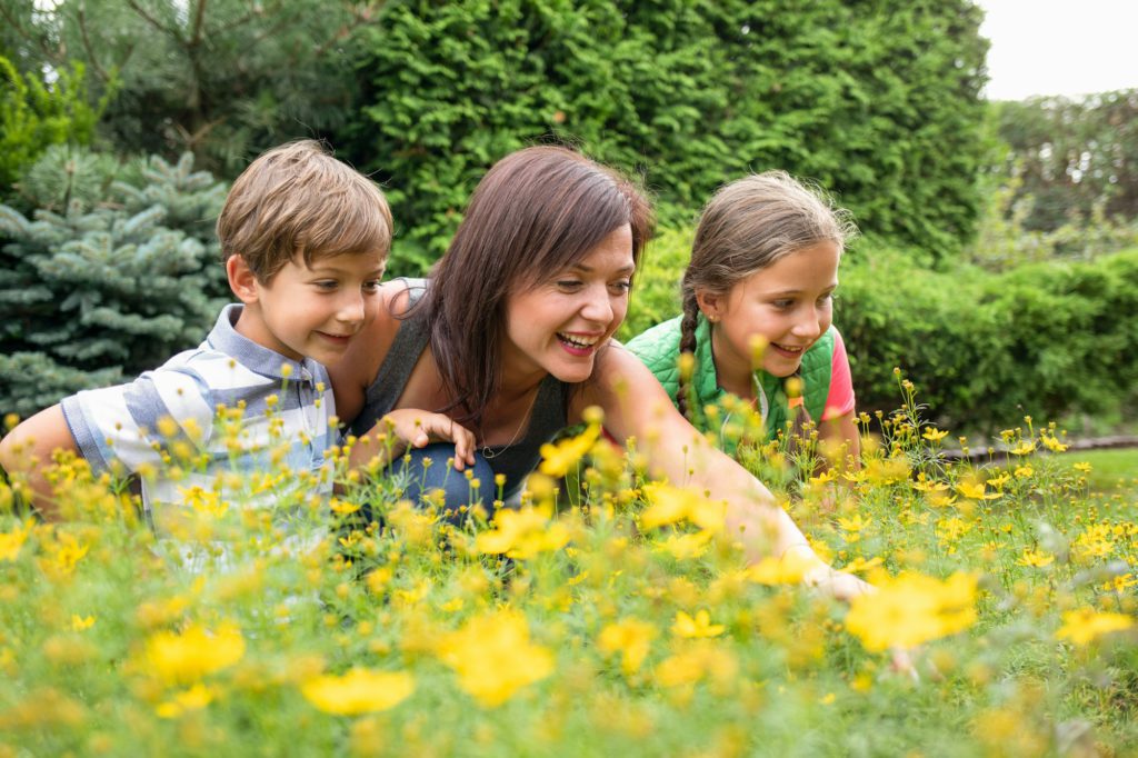 Mom son and daughter in backyard garden happy looking at plants